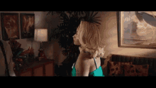 a woman in a green dress stands in a living room
