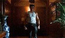 a man in a tank top is holding his claws out in a hallway