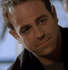 a close up of a man 's face with a black shirt on