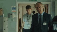a man and a woman are walking in a hallway and the man has a name tag that says ' a. '