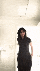 a woman in a black shirt and black pants is dancing in a room .