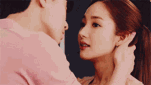 a man is touching a woman 's ear while they kiss .