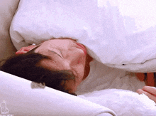 a man is laying on a bed with his head on a pillow and his eyes closed .