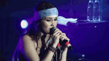 a woman singing into a microphone with a headband on