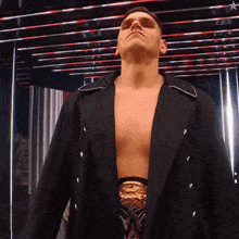 a shirtless wrestler in a black coat and gold belt