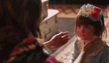 a little girl wearing a headband is being touched by another girl