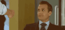 a man in a suit and tie is looking up at something while another man shakes his hand .