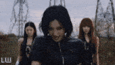 a group of women are standing in a field and the word luw is on the bottom right