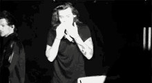 a black and white photo of a man with long hair dancing on stage .