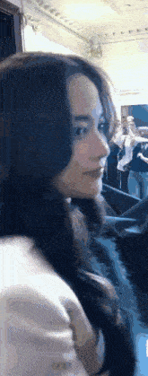 a close up of a woman 's face in a room with a crowd behind her