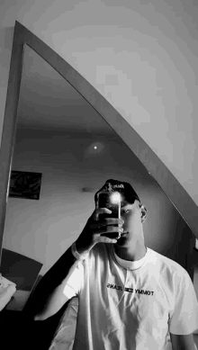 a man is taking a selfie in front of a mirror while wearing a hat .