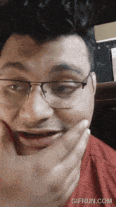 a man wearing glasses and a red shirt is making a funny face with gifrun.com at the bottom