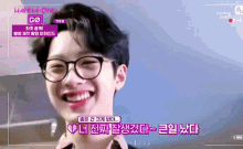a young man wearing glasses is smiling with korean writing on the bottom right