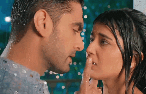 a man and woman are kissing in the rain and the woman is covering her mouth with her hand