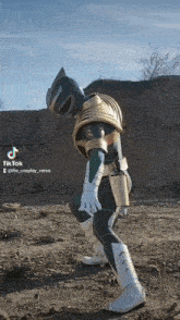 a person in a green and gold power ranger costume is standing in a dirt field