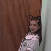 a girl in a school uniform has a cat ear headband on her head .