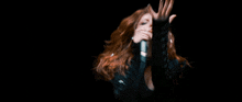 a woman is singing into a microphone with her hair blowing in the wind