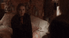 a woman sitting on a bed with a scarf around her neck that says ' i love you '