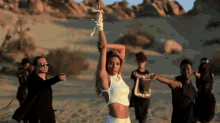 a woman in a white crop top stands in the middle of a group of people