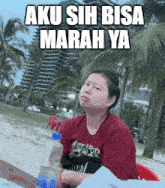 a woman sits at a table with a bottle of water and the words aku sih bisa marah ya written above her