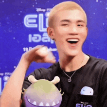 a man is holding a stuffed animal in front of a sign that says ' eli '
