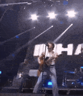 a man singing into a microphone while playing a guitar on a stage