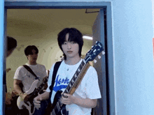 a young man is holding a guitar and wearing a shirt that says ' more ' on it .