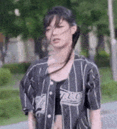 a young woman wearing a baseball jersey and a crop top is walking down the street .