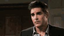 a man in a suit and a blue shirt is looking at the camera .