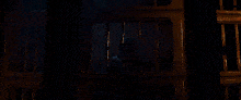 a woman is behind bars in a dark room and looking through the bars .