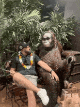 a man is sitting on a bench next to a statue of a monkey