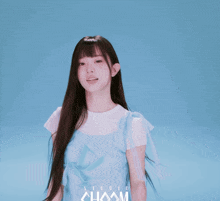 a girl in a blue dress stands in front of a blue background that says studio chaam on it
