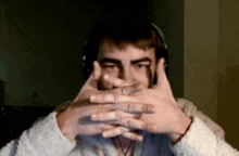 a man wearing headphones covering his face with his hands