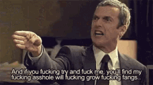 a man in a suit and tie is making a funny face and pointing his finger .