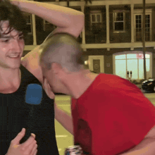 a man in a red shirt is being interviewed by another man with a microphone