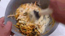 a person is mixing vegetables in a bowl with a spoon and the words made in animatica on the bottom .