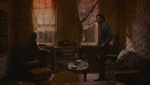 a man standing in a living room next to a woman sitting in a chair