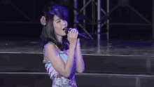 a woman sings into a microphone on a stage