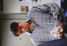 a man in a plaid shirt holds a stack of money