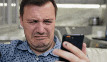 a man is making a funny face while looking at his cell phone