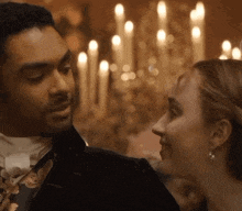 a man and a woman are looking into each other 's eyes in front of candles