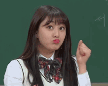 a girl in a school uniform is making a funny face in front of a chalkboard