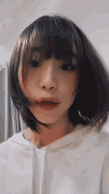 a girl with short hair is wearing a white hoodie and making a funny face