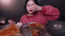 a woman is eating a plate of food with chopsticks .