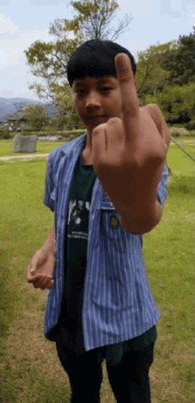 a boy in a striped shirt giving the middle finger to the camera