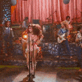 a woman is singing into a microphone while a man plays a guitar