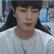 a man wearing headphones and a necklace is looking at the camera .