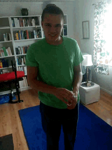 a man in a green shirt is standing in front of a bookcase