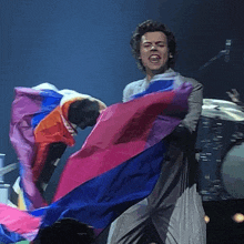 a man is holding a bisexual pride flag on a stage .