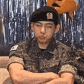 a man in a military uniform is sitting with his arms crossed .